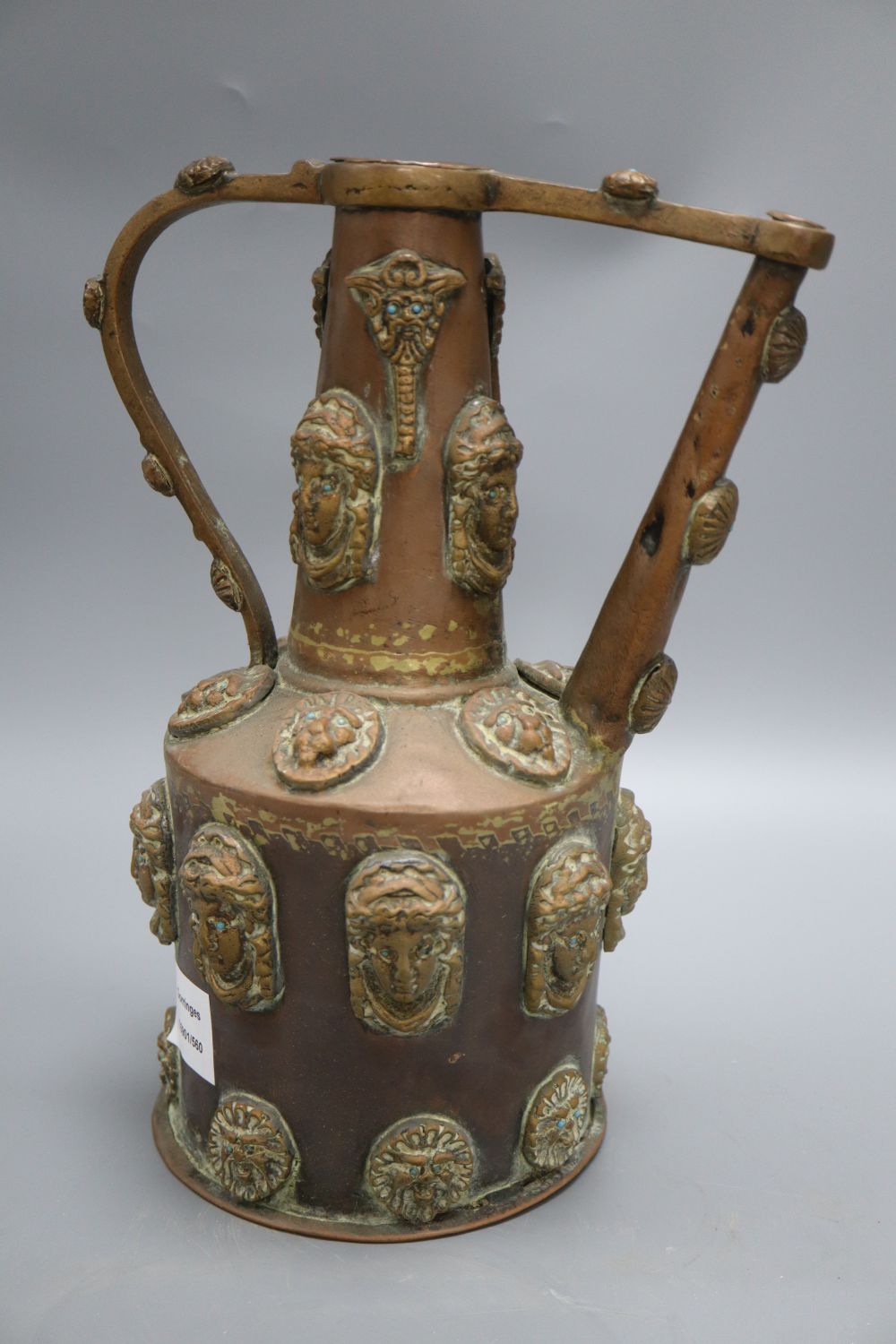 A Middle Eastern copper pot, decorated with classical ladies and lions faces with turquoise beaded eyes, height 32cm